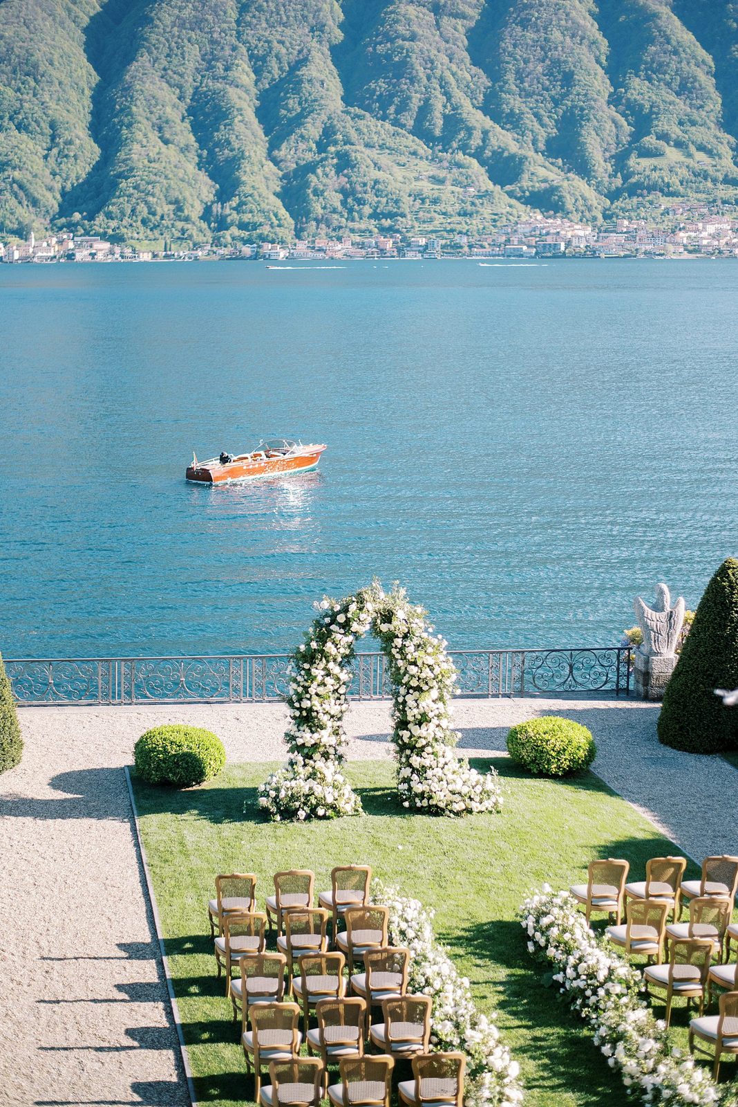 Ceremony chairs and a white floral arch on a terrace above Lake Como